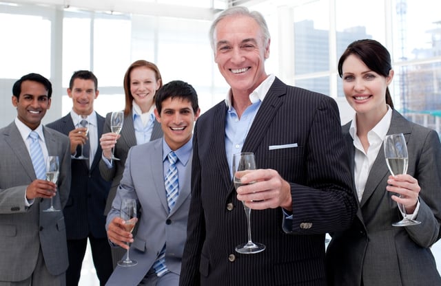 Smiling inernational business team holding glasses of Chamoagne to celebrate a success.jpeg